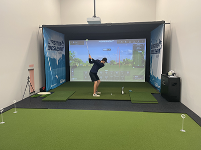 A member of the golf team takes a swing in the Eric Nyman Performance Golf Center.